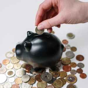 person putting coin in a piggy bank